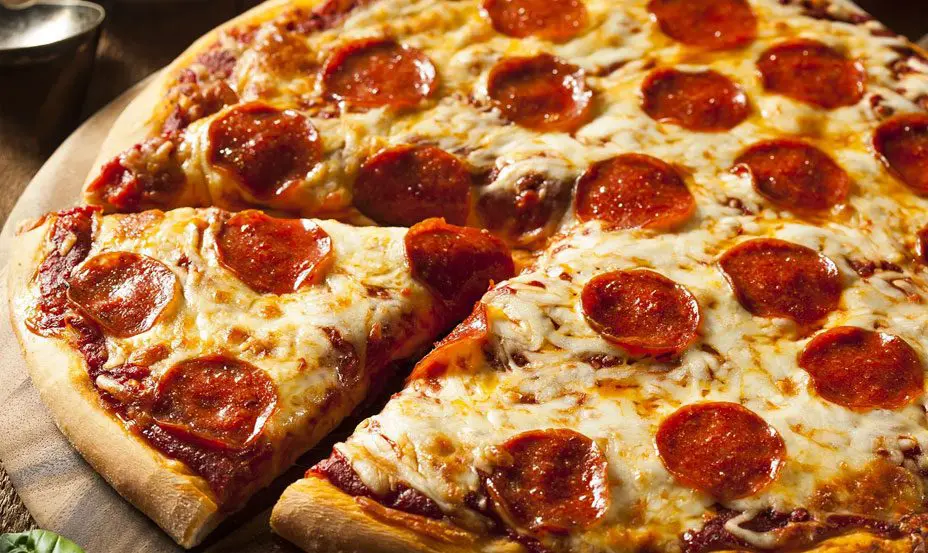 Close-up of a freshly baked pepperoni pizza with a slice being lifted, showing melted cheese and toppings.