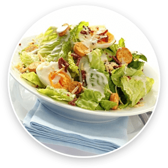 A caesar salad with croutons, parmesan cheese, and dressing in a white bowl, accompanied by a blue napkin.