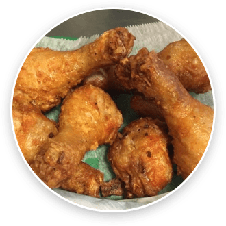 A plate of fried chicken drumsticks on a paper towel, viewed from above.