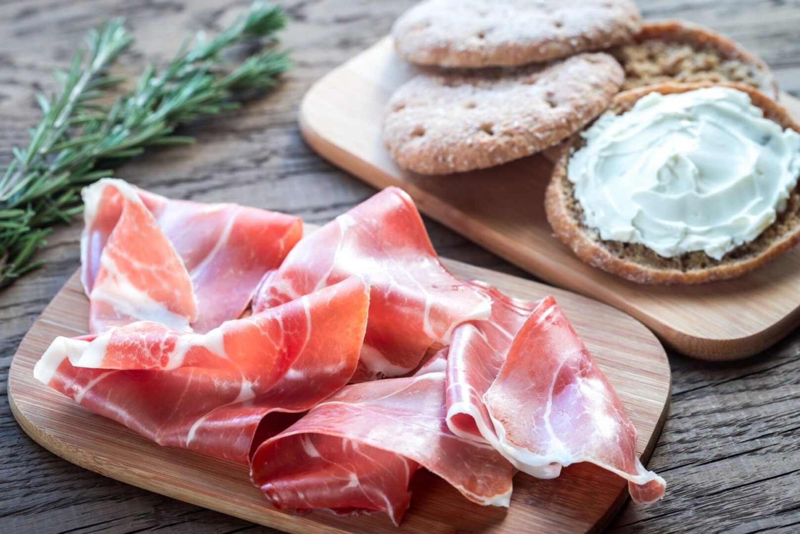 Freshly sliced ham and bread on a wooden cutting board.