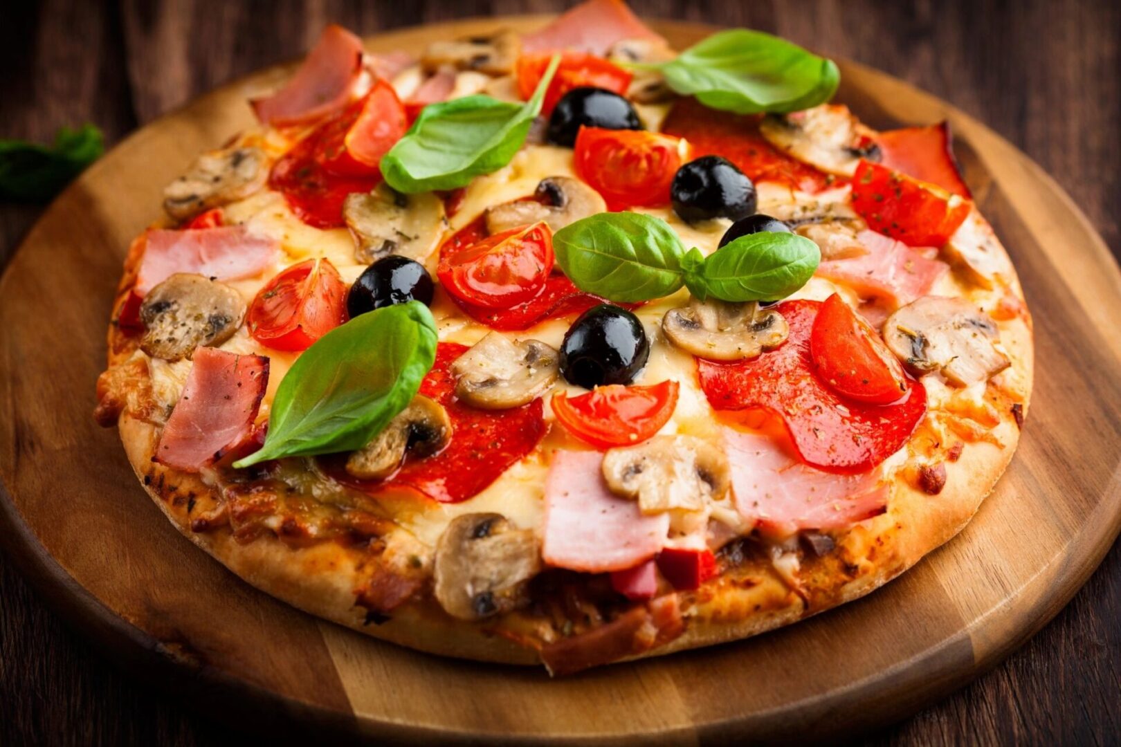 A delicious pizza topped with tomatoes, mushrooms, olives, and basil.