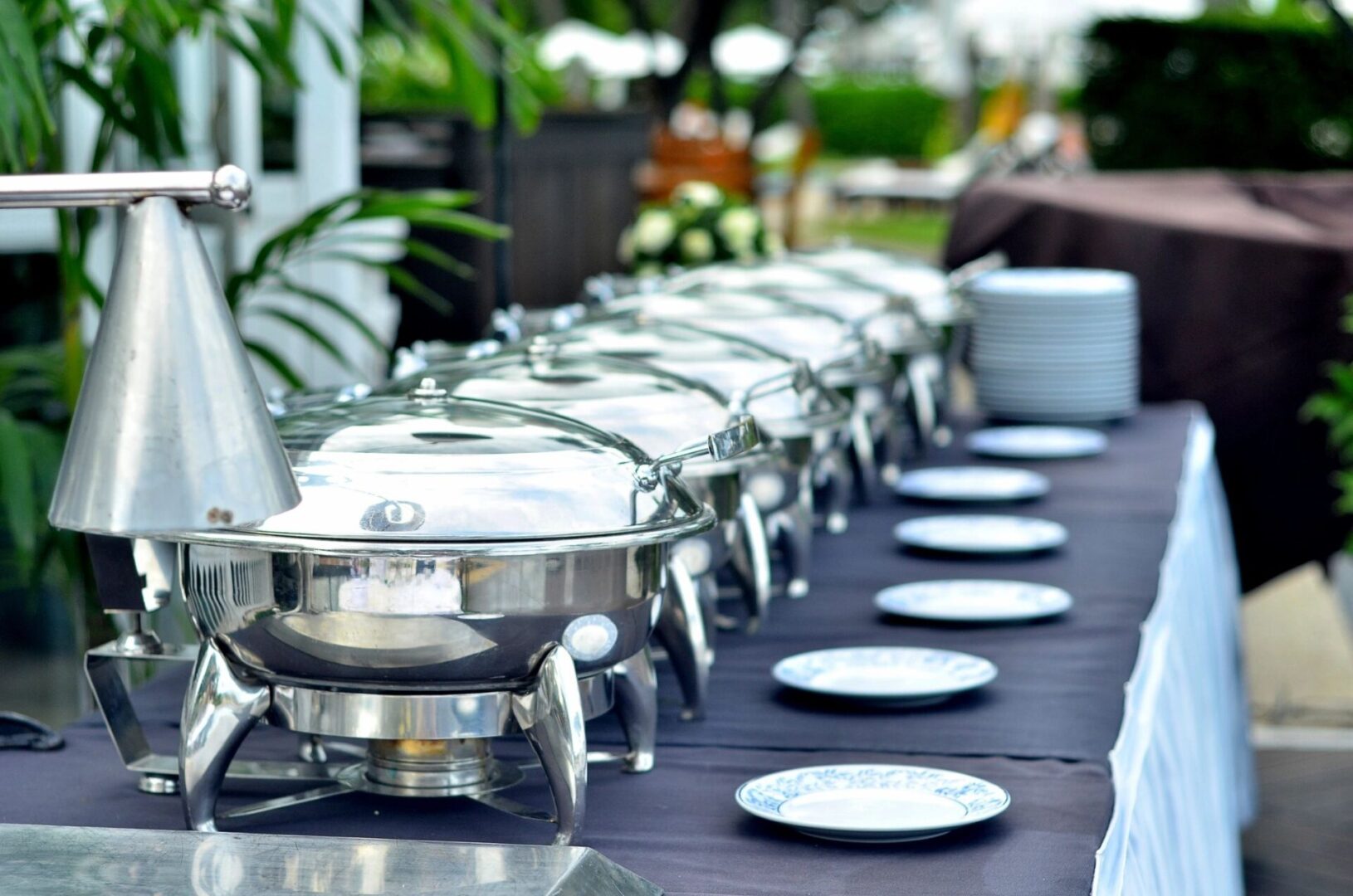 A long table set with silver dishes and plates.