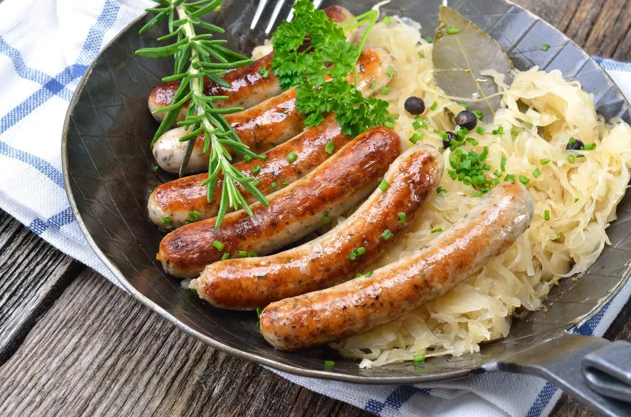 A pan of sausage and rice with herbs on the side.