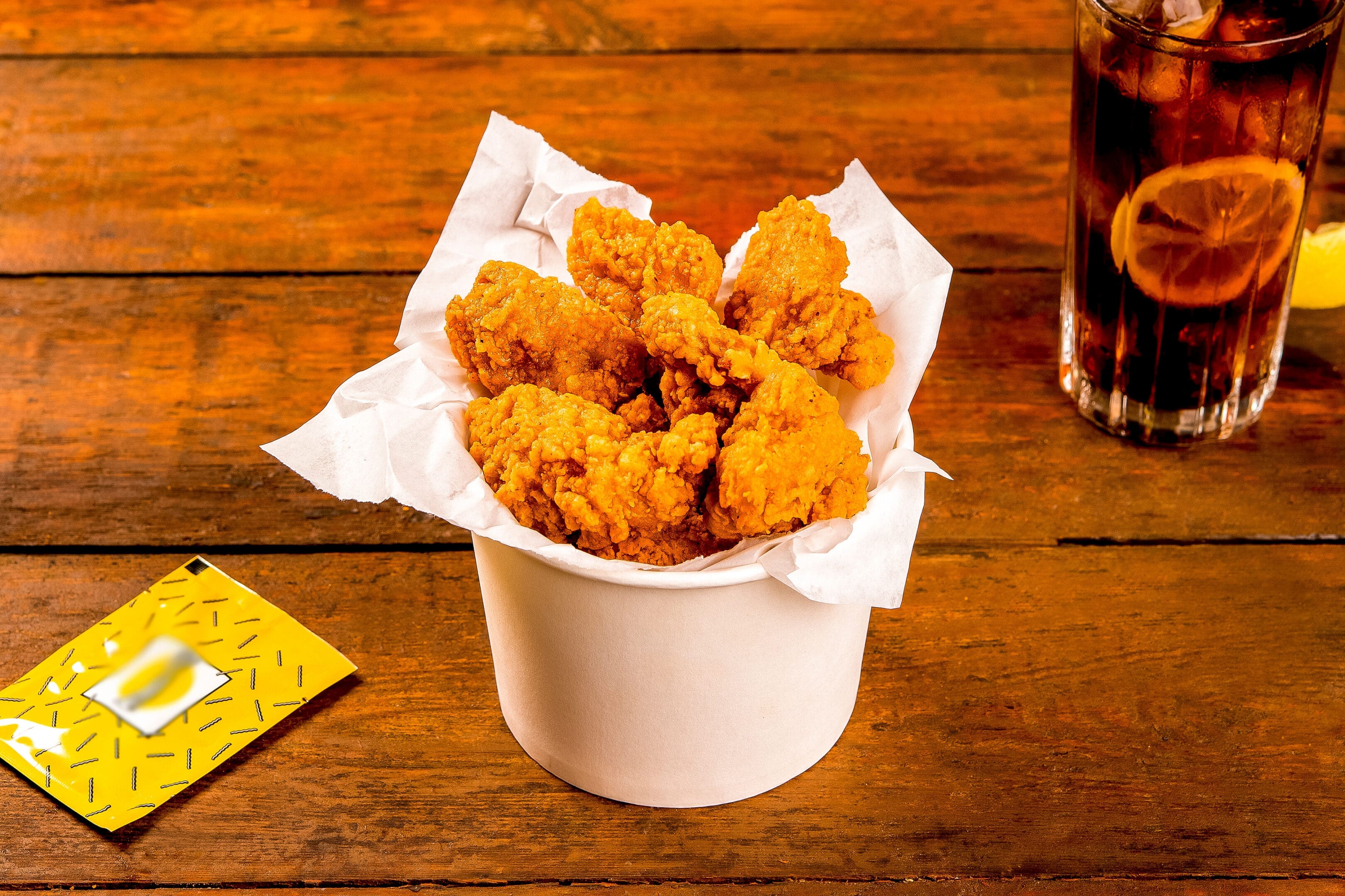 Bucket of crispy fried chicken on wooden table