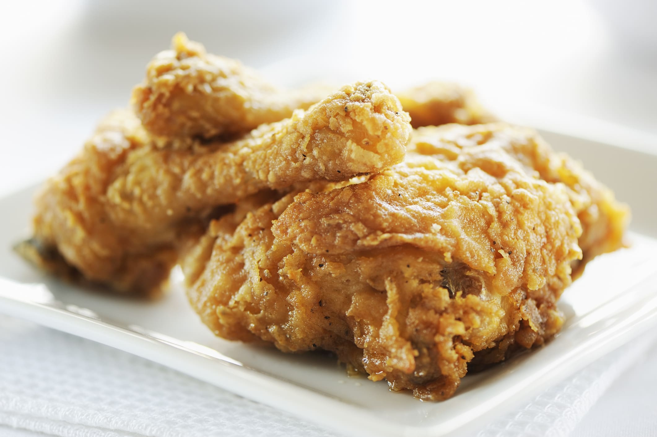 Crispy fried chicken drumsticks on white plate