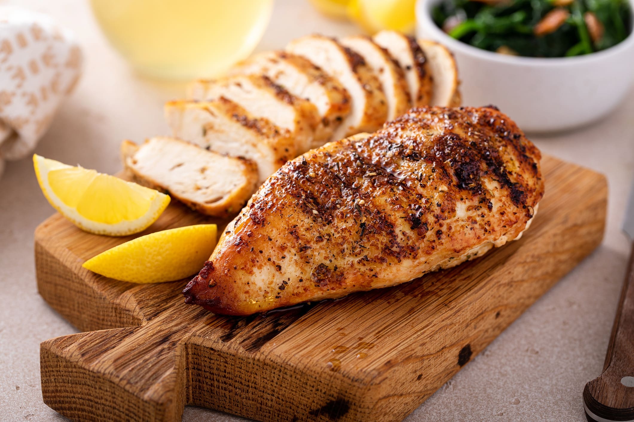 Seasoned grilled chicken breast with lemon wedges