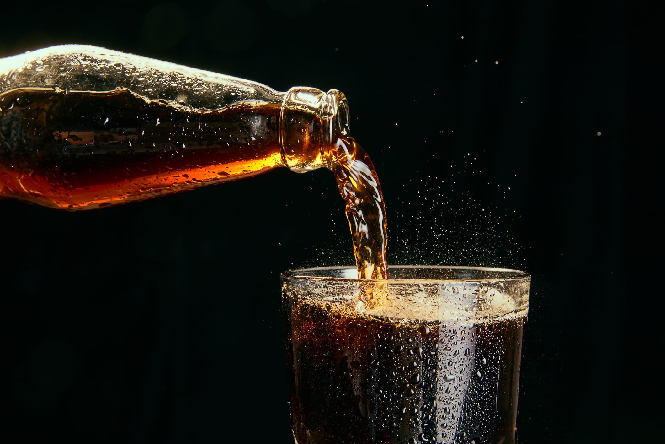 Cola being poured from bottle into glass